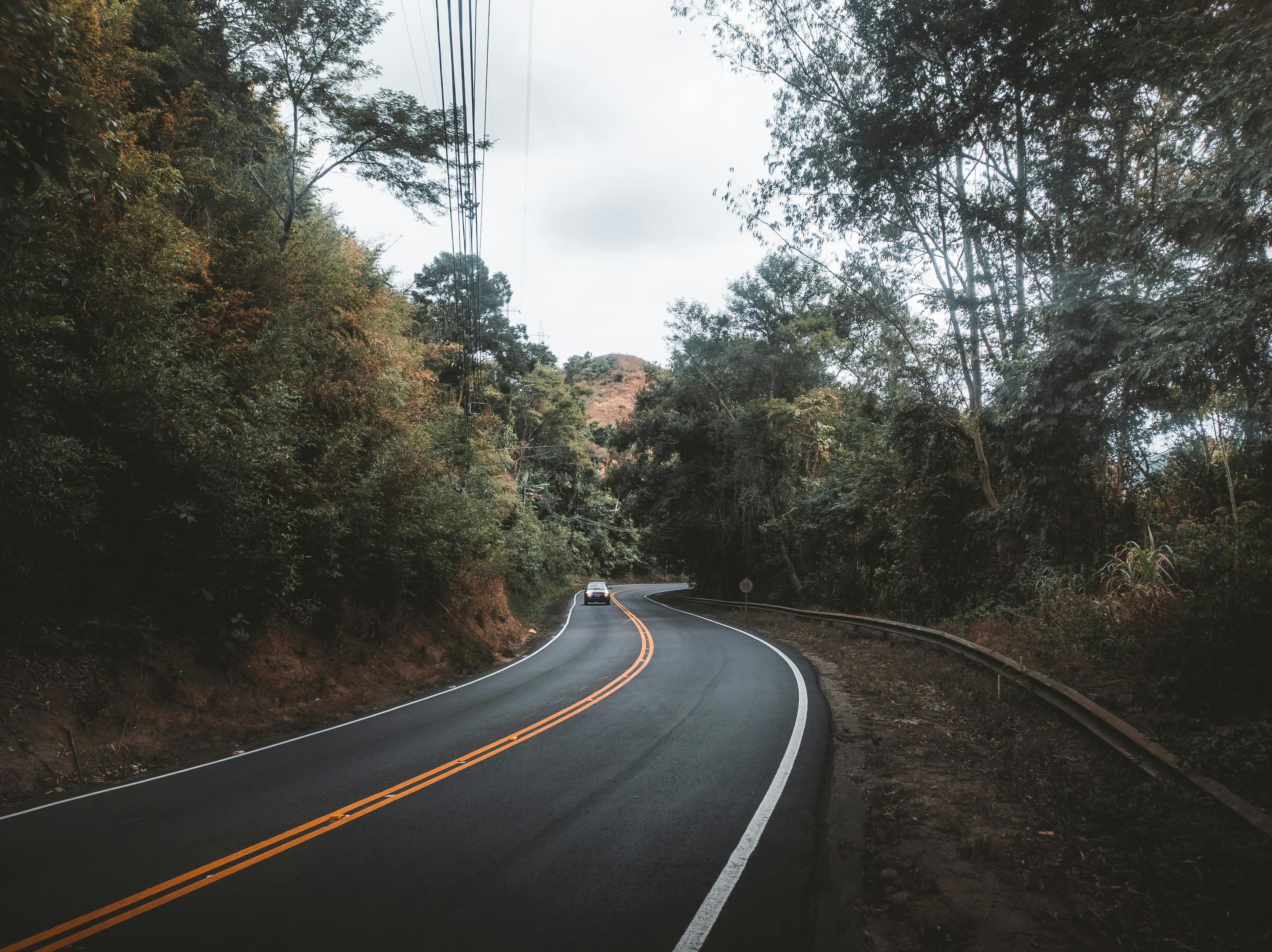 Aerial view of a car on a winding road through green hills